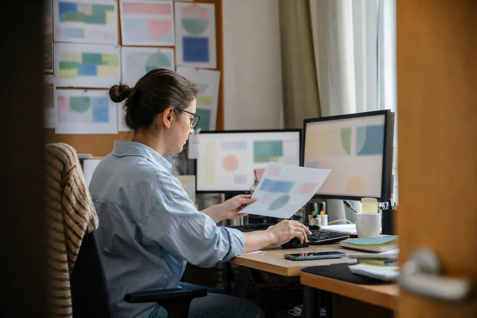 Analityczka porównuje w arkuszu oferty i reklamy kilku firm na dwóch monitorach